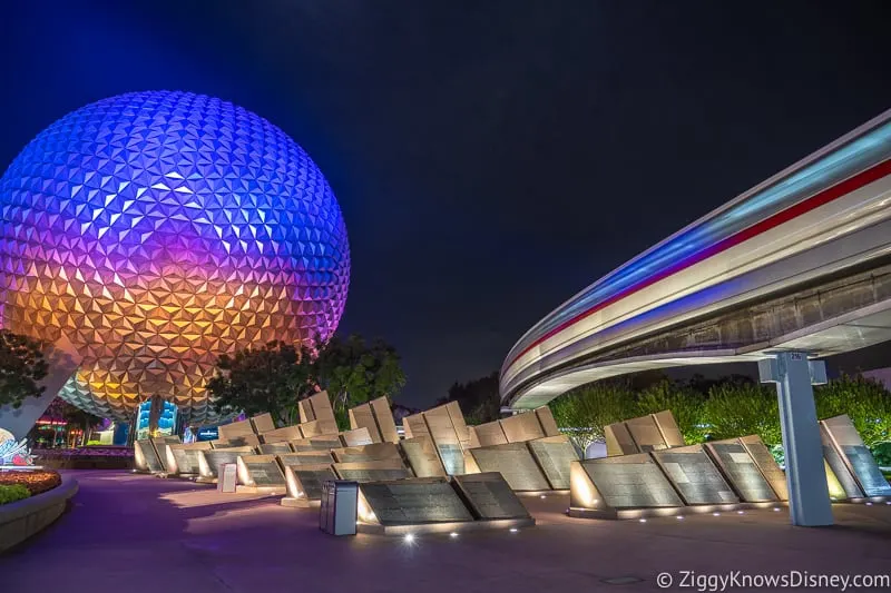 Spaceship Earth at night with the monorail passing over the Leave a Legacy Monuments