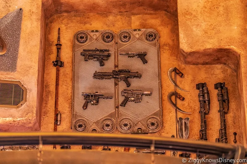 blasters on the wall of Dok Ondar's Den of Antiquities Galaxy's Edge