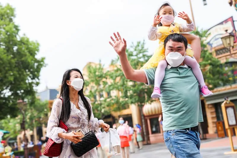 family walking through Disney Park with face masks