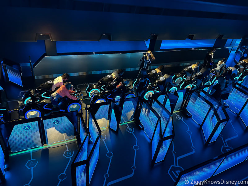 riders loading onto TRON Lightcycle ride vehicles