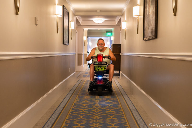 riding a scooter down the hallway in a Disney Resort
