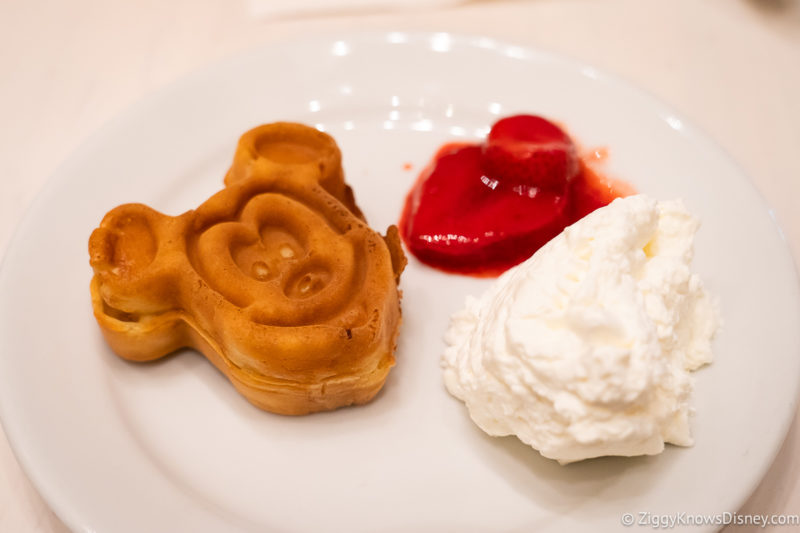 Mickey Mouse Waffle on a plate with whipped cream and strawberries