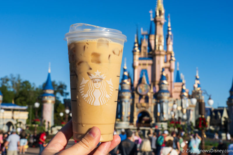 holding up a Starbucks coffee in front of Cinderella Castle Magic Kingdom