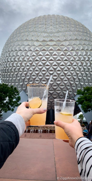 holding up drinks in front of Spaceship Earth EPCOT