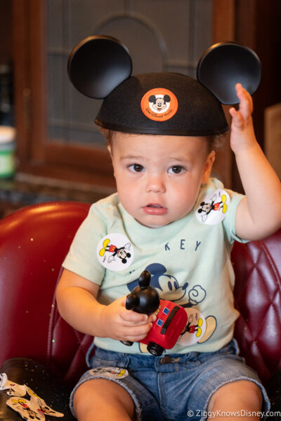 cute baby in chair with Mickey Mouse hat at Main Street Barber Magic Kingdom